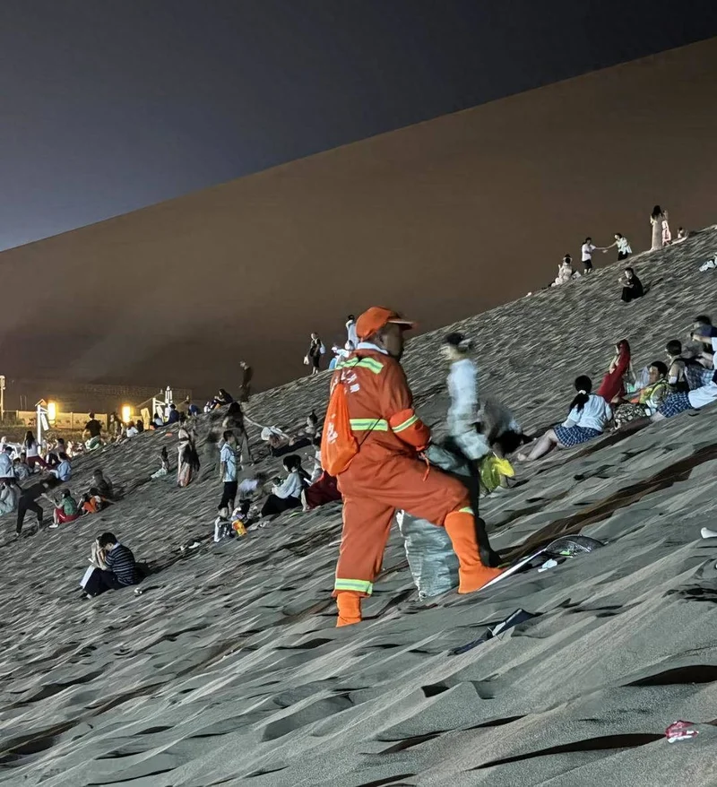 敦煌鸣沙山游客散去留下遍地垃圾 环卫工深夜上山清运